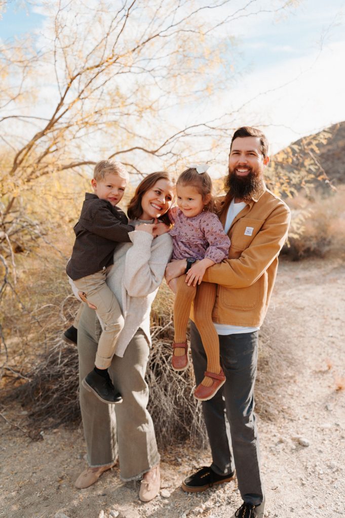 Founders of Cram Jams, Andy and Amelia Carpenter, with their children Elvis and Etta, standing in a desert landscape near their home.